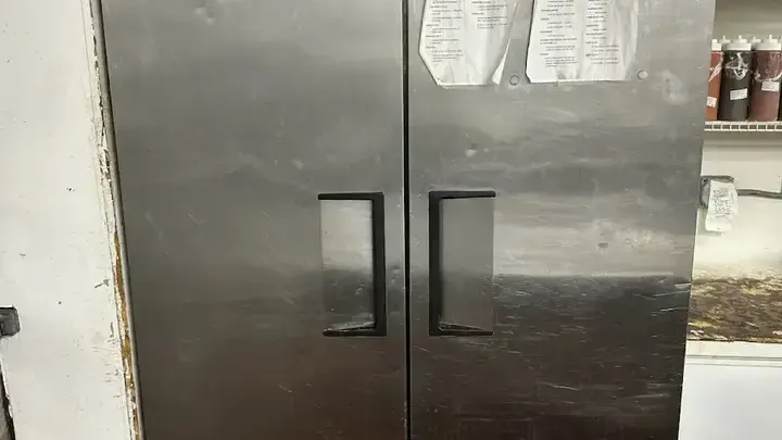A stainless-steel reach-in cabinet in a working foodservice space.