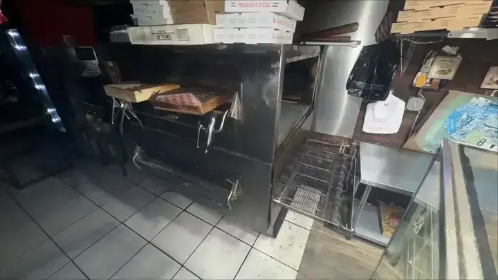 A stainless-steel pizza oven alongside preparation space and pizza boxes.