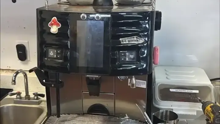 A commercial coffee station with touchscreen controls and beverage outlets.