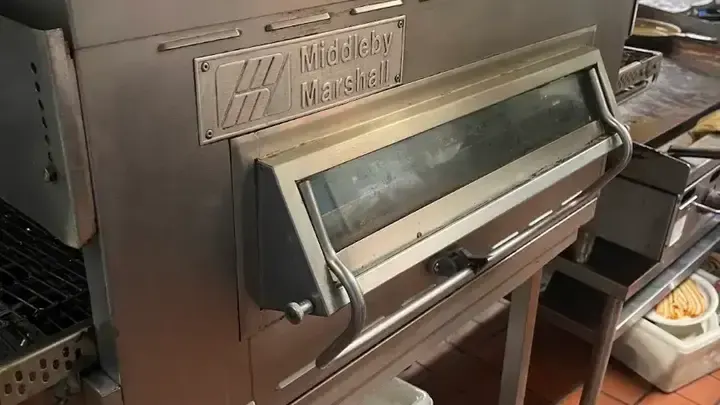 A Middleby Marshall oven with a conveyor and front access window.