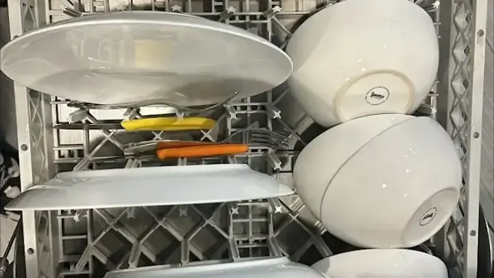A loaded dishwashing rack with plates and utensils.