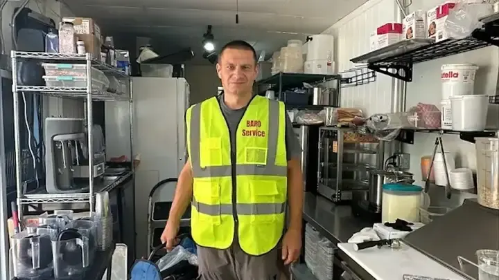 A technician wearing a BARO Service vest beside foodservice equipment and supplies.