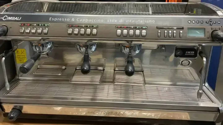 A LaCimbali espresso machine with three brewing groups and a bank of drink controls.